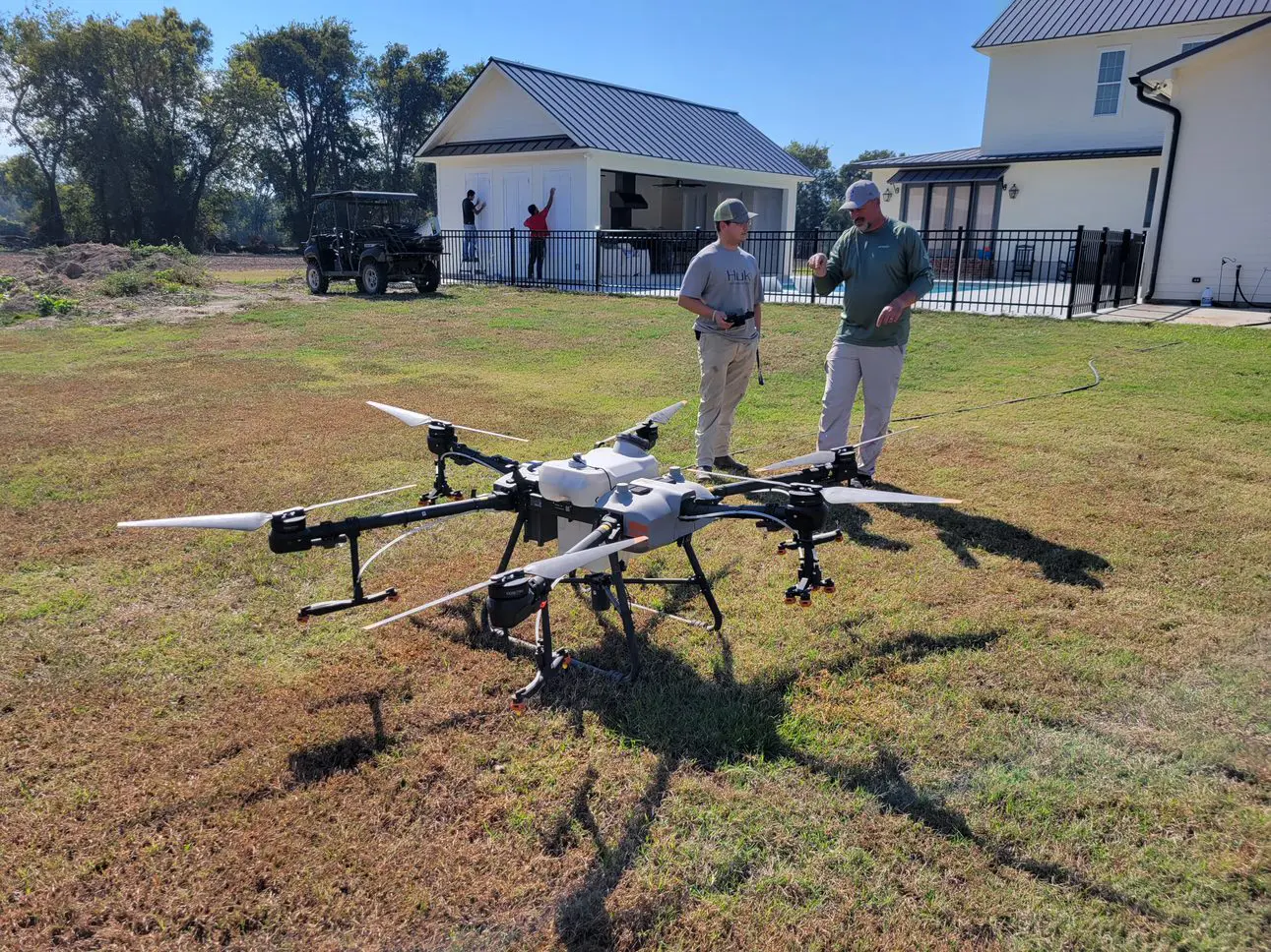  Two men talk behind a large drone with four propellers. 
